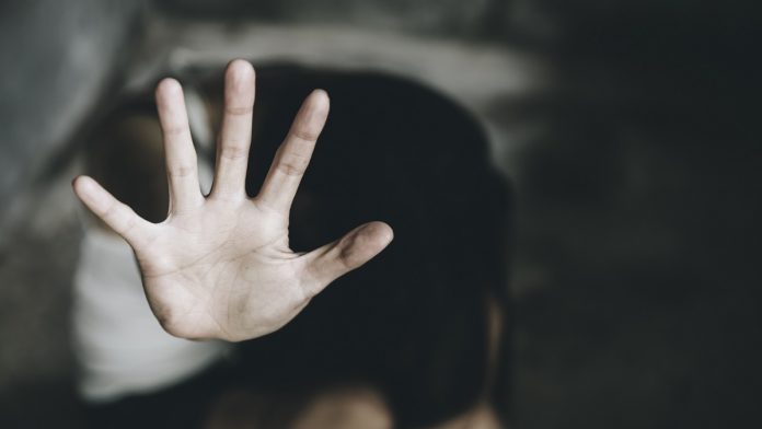 Close-Up Of Woman Showing Stop Sign While Sitting Indoors