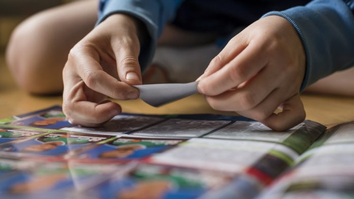 8 year old boy pasting soccer trading cards into his scrapbook